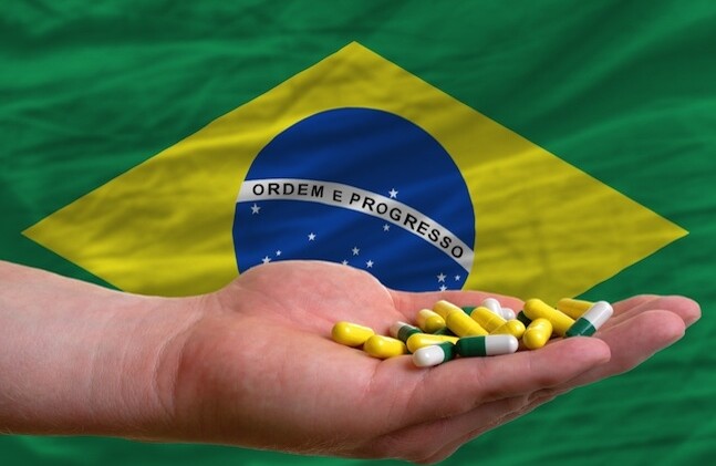CREDIT: <a href="http://www.shutterstock.com/pic-106093970/stock-photo-man-holding-capsules-in-front-of-complete-wavy-national-flag-of-brazil-symbolizing-health-medicine.html">Shutterstock</a>