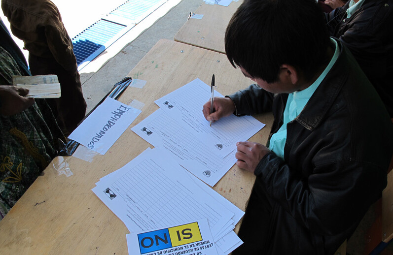 2010 年 10 月，危地马拉卡布里坎的一名社区投票工作人员记录公投参与者的姓名并分发选票。图片来源：凯瑟琳-富尔茨