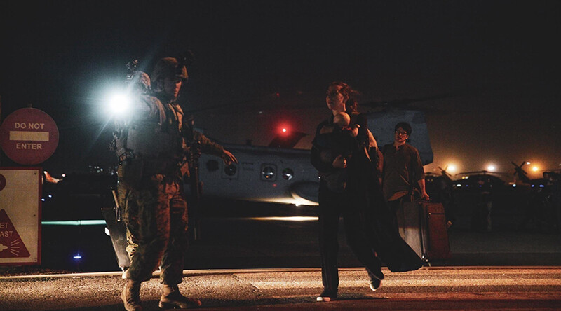 A United States Marine escorts a Department of State employee to evacuation at Hamid Karzai International Airport, Kabul, Afghanistan, August 15, 2021. CREDIT: <a href="https://en.wikipedia.org/wiki/File:Afghanistan_withdrawal_Image_3_of_7.jpg">Sgt. Isaiah Campbell/Public Domain</a>