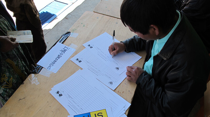 A community poll worker in Cabrican, Guatemala records the names of participants in the referendum and hands out ballots, October 2010. CREDIT: Katherine Fultz