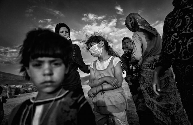 Comté de Varzaqan, Iran. 2012 - Cette petite fille a perdu sa mère dans le tremblement de terre. Alors que d'autres femmes tentent de la réconforter, elle porte un masque pour se protéger de la poussière et de la puanteur.