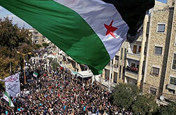 Syria independence flag flies over protesters in Idlib, <br>CREDIT: <a href="http://www.flickr.com/photos/syriafreedom/6961997081/">Freedom House</a> (<a href="http://creativecommons.org/licenses/by/2.0/deed.en">CC</a>)