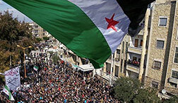 Syria independence flag flies over protesters in Idlib, <br>CREDIT: <a href="http://www.flickr.com/photos/syriafreedom/6961997081/">Freedom House</a> (<a href="http://creativecommons.org/licenses/by/2.0/deed.en">CC</a>)